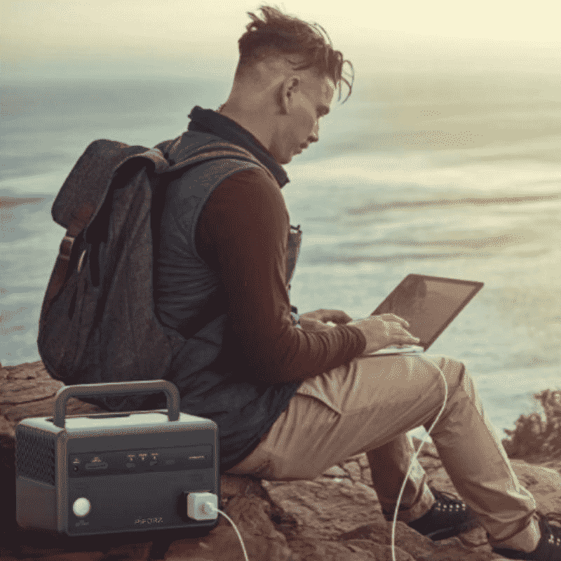 Estación de energía portátil PF300 junto a un usuario trabajando con una laptop frente al mar.