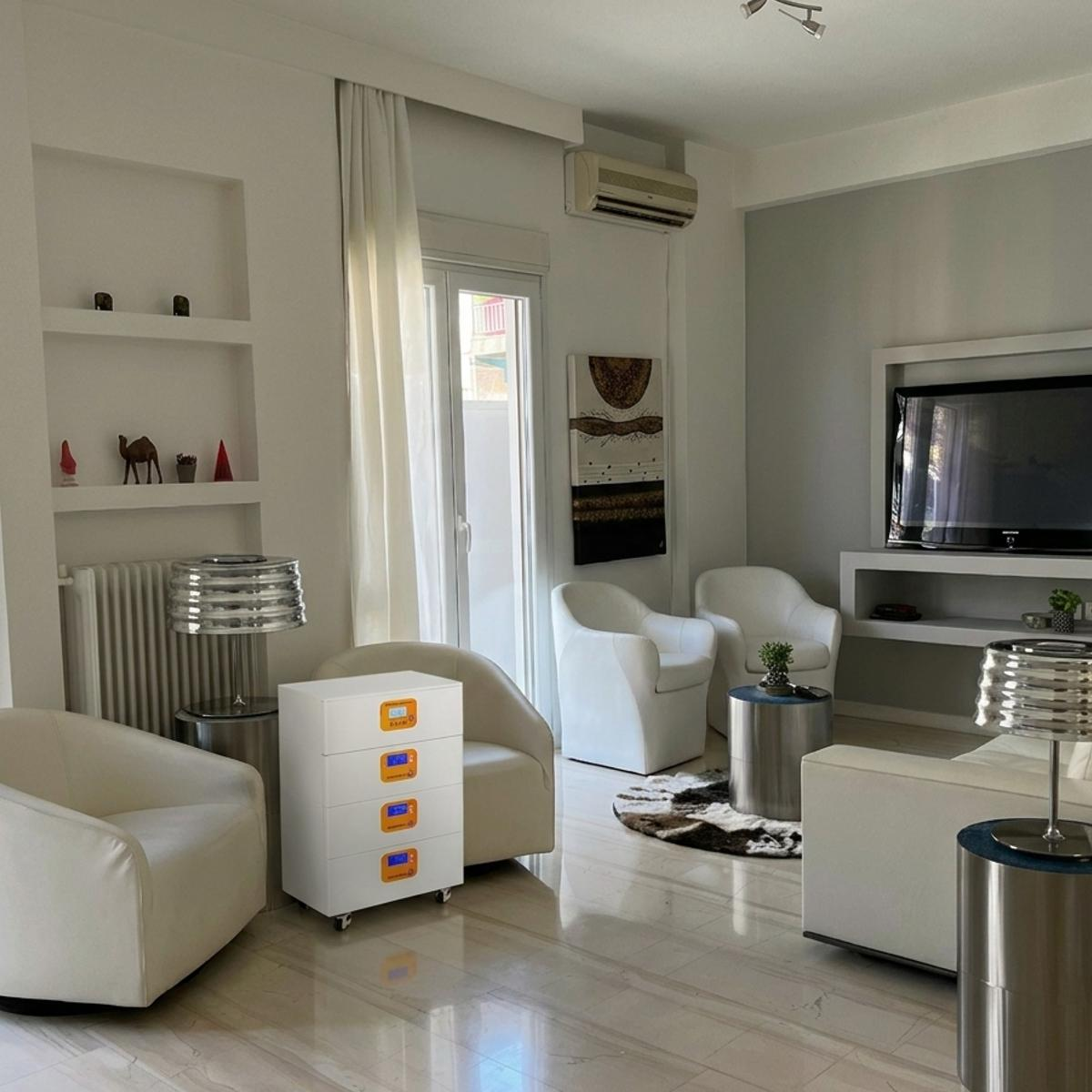 Un moderno sistema de almacenamiento de energía en baterías de color blanco con tres módulos apilables, ubicado discretamente en una sala de estar minimalista. El equipo cuenta con pantallas LCD de monitoreo y ruedas para facilitar su movilidad en interiores residenciales.