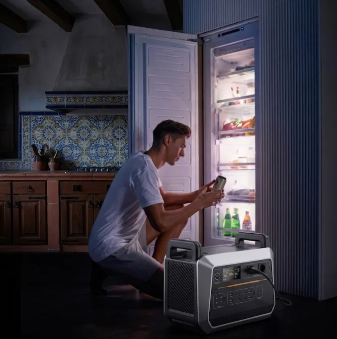 Hombre utilizando una estación de energía portátil de gran capacidad para alimentar la nevera de la cocina durante un apagón.