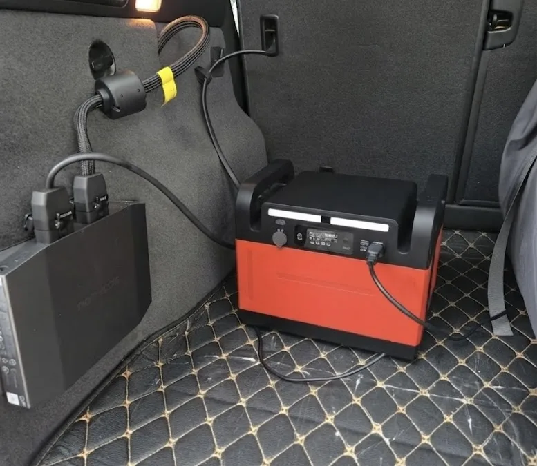 車の荷室に置かれ、専用ケーブルで車載充電されているポータブル電源。