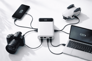 A central Piforz power station charging a smartphone, a DSLR camera, a drone, and a laptop at once through multiple USB ports.