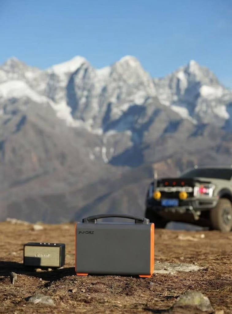A Piforz portable power station powering a camping fridge and lights next to an electric vehicle, preserving the EV's battery for the drive home.