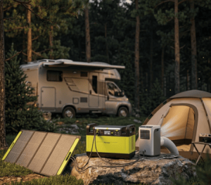 A lime green portable power station connected to a solar panel and powering a small portable air conditioner outside a tent and RV in a forest setting.