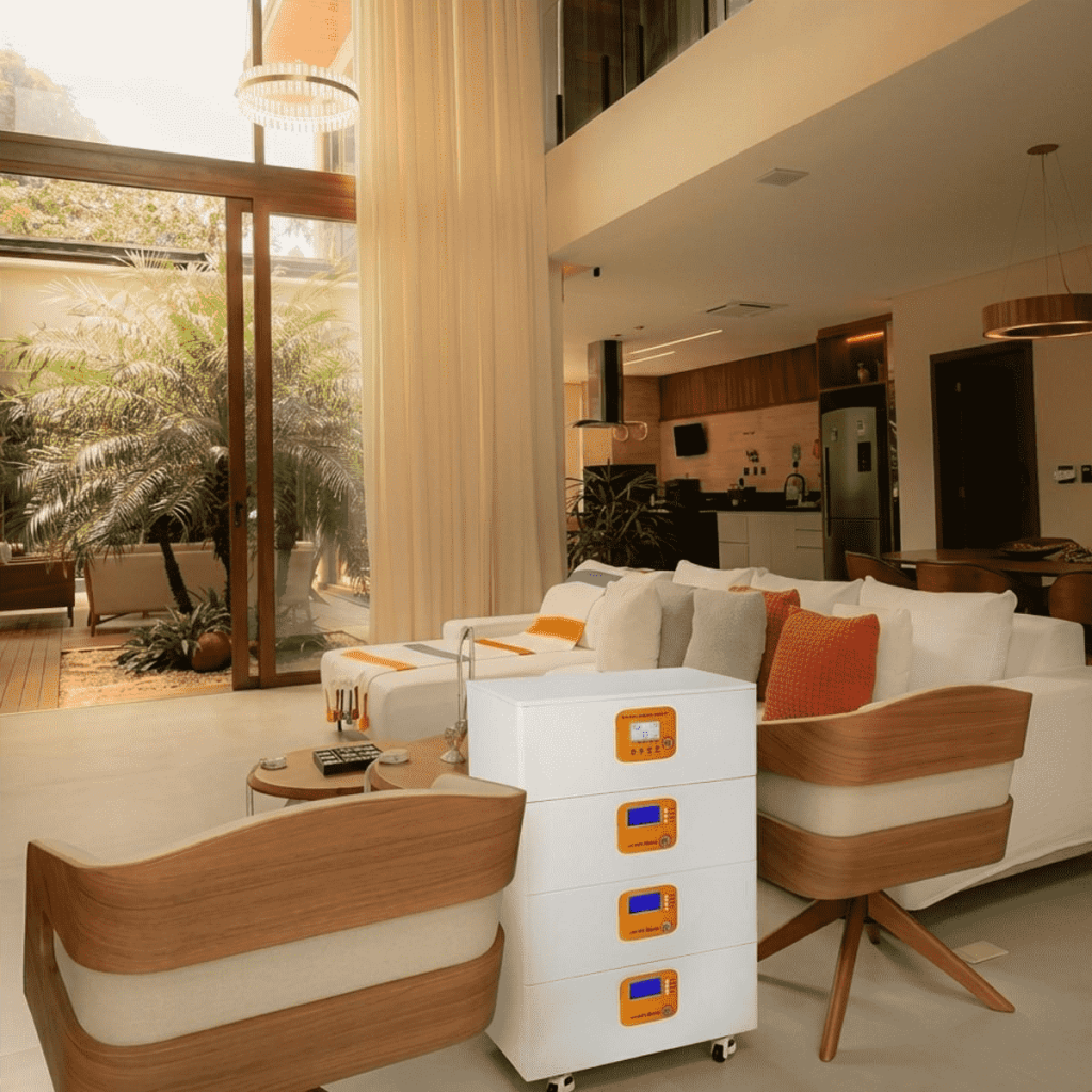 A 4-module white ESS system on wheels located in a bright, luxury open-concept living room and kitchen. The energy storage unit is positioned as a functional furniture-like appliance for smart home energy management.