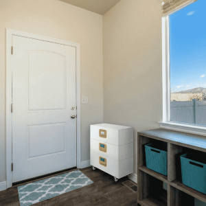 A white, modular ESS system with three stacked LiFePO4 battery modules on wheels, placed in a modern home entryway near a doorway. This portable energy storage system provides reliable backup power for residential use.