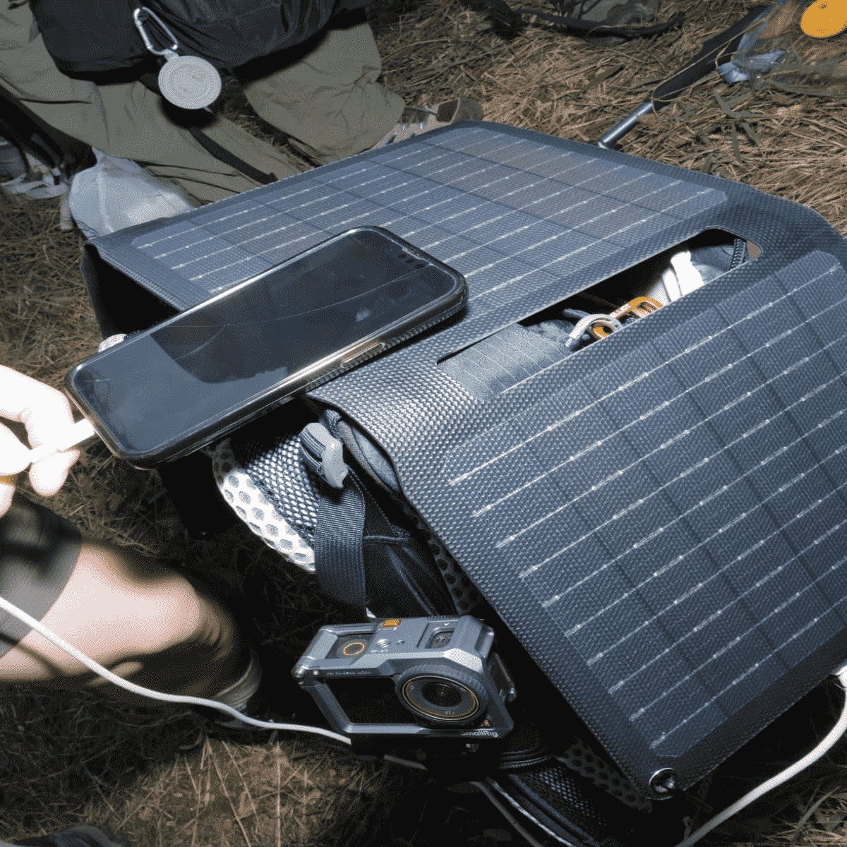 A lightweight portable solar charger for phone attached to a backpack during a hike