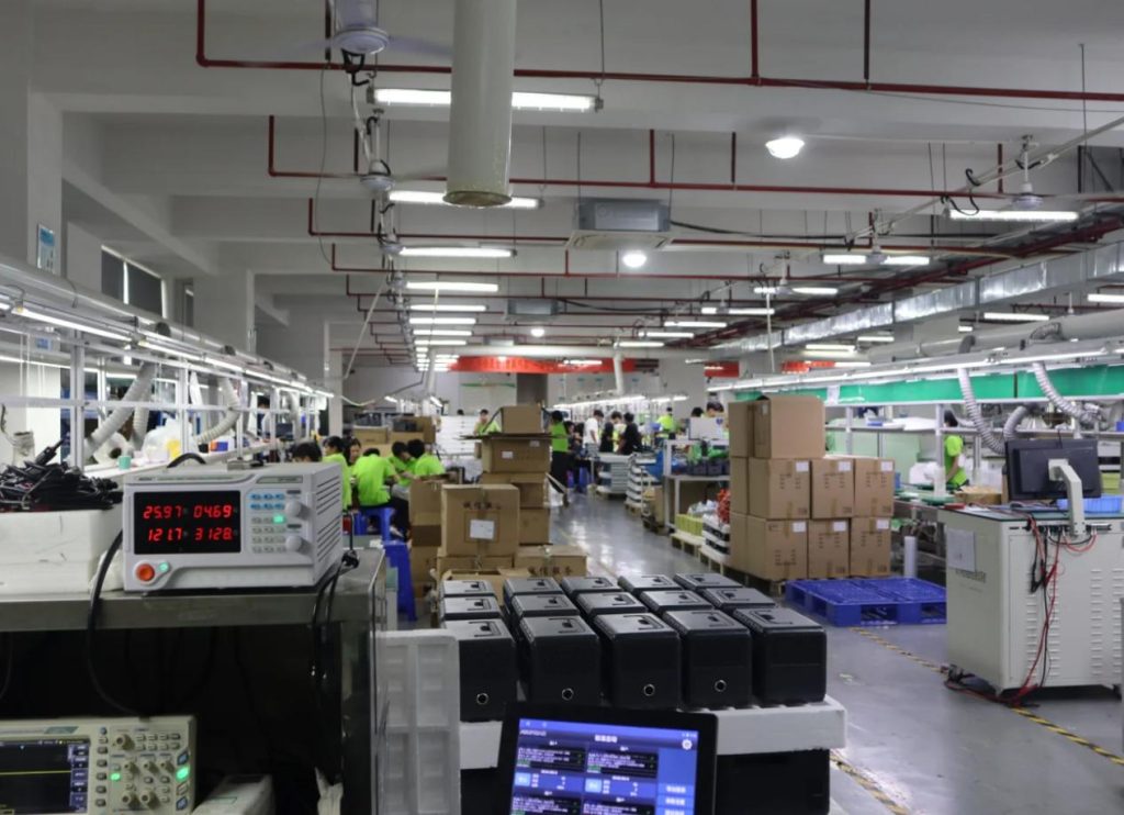 Technicians assembling and testing high-quality portable solar power generators inside a manufacturing workshop to ensure battery safety.