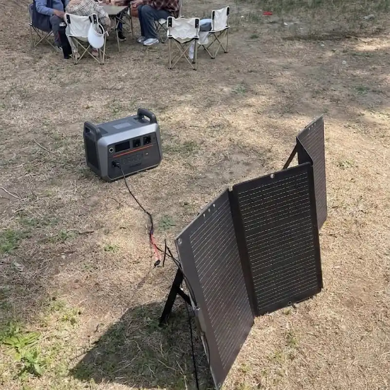 Portable power station connected to solar panels in a campsite.