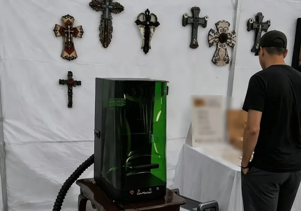A vendor operating a laser engraver inside a craft fair booth powered by a portable power station.