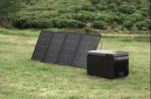 Foldable 200W solar panel set up on grass connected directly to a portable outdoor refrigerator.